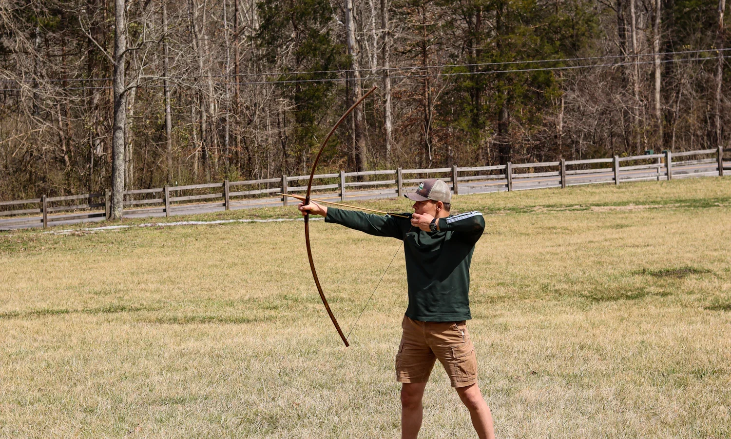 Archer at full draw with a longbow in an open field
