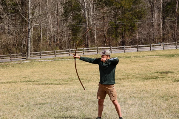 Archer at full draw with a longbow in an open field