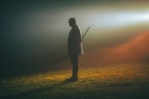 Silhouette of a person holding a bow in mist at dusk