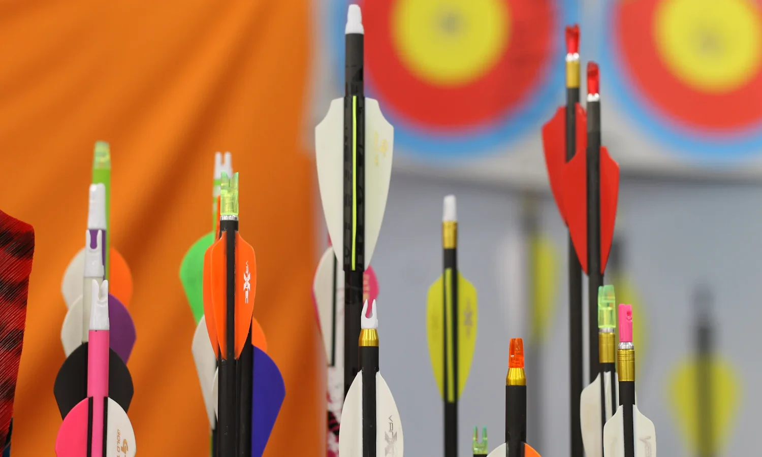Arrows with colourful fletching standing in an archery target