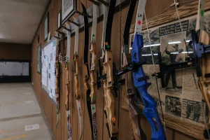 Recurve bows hanging on a wall rack at an indoor archery range
