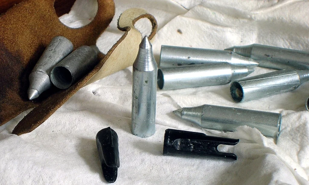 Arrow field points and plastic nocks laid out beside a leather finger tab