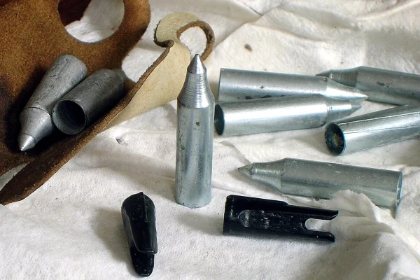 Arrow field points and plastic nocks laid out beside a leather finger tab