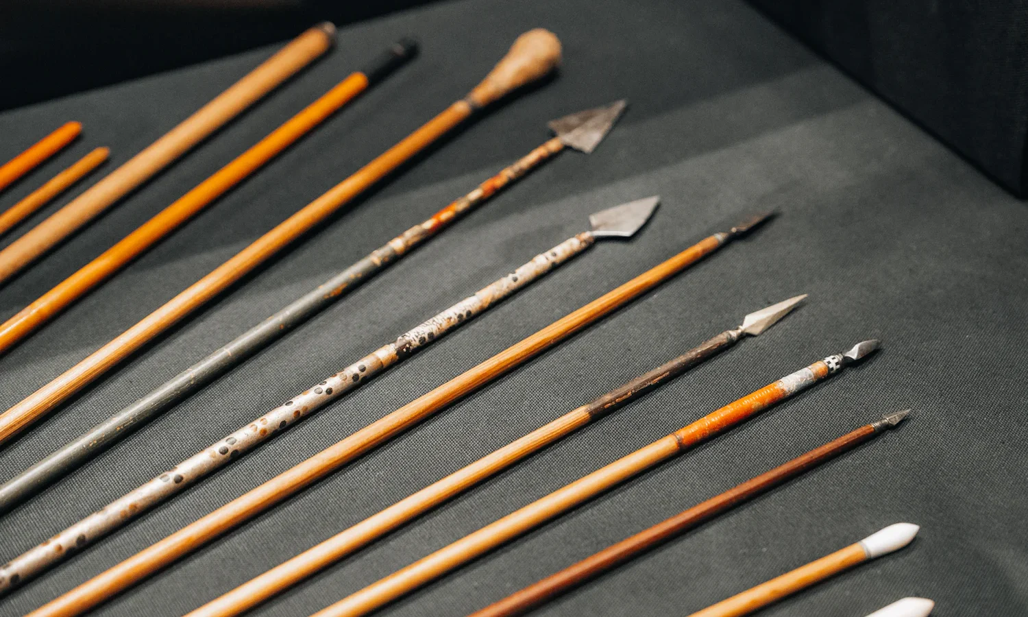 Wooden arrows with assorted metal points laid out on a dark table